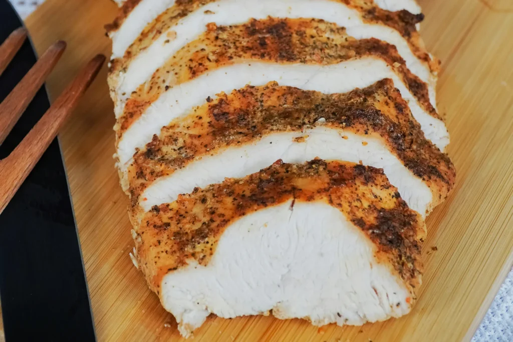 Sliced roasted turkey breast on a wooden cutting board.