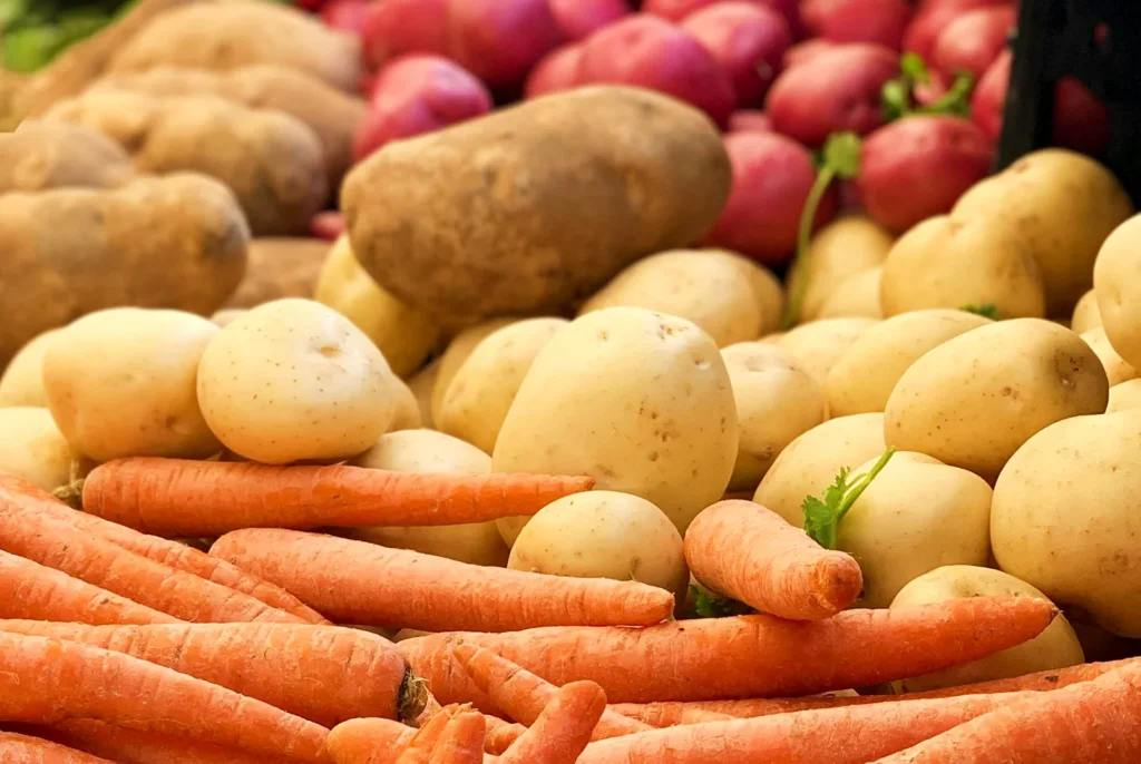 Assorted potatoes and carrots on display at a market.